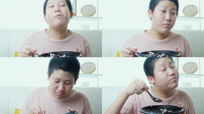 亚洲男孩在家沙发上吃美味的巧克力蛋糕，生活方式理念。