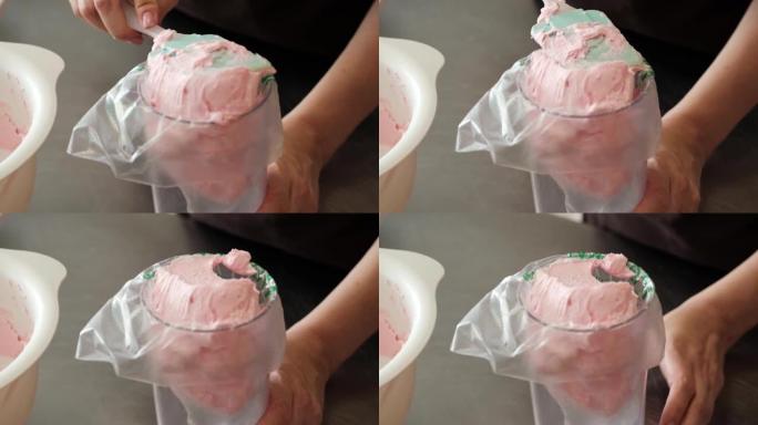 4k女糕点厨师将粉红色奶酪奶油放入糕点袋中，特写镜头。慢动作。蛋糕制作过程。