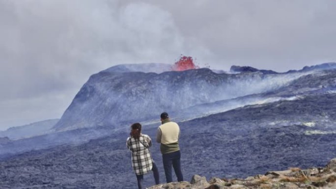 大胆的冒险家观察火山爆发和雄伟的多云天空