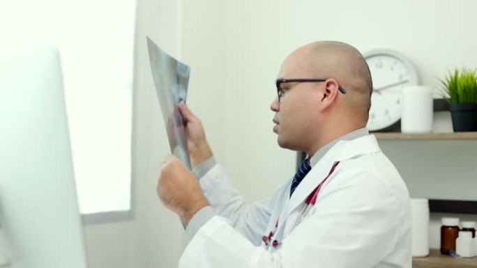 年轻的亚洲医生在家工作，看起来像x光片。通过视频会议在线报告患者的x射线症状和结果。