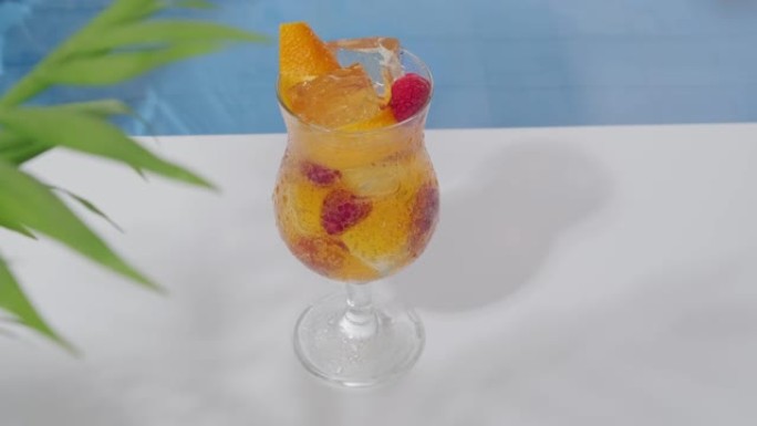 明亮凉爽的橙色鸡尾酒，配有覆盆子和游泳池边的冰块。爽肤饮料。炎热夏日的软饮料。夏天的海滩派对