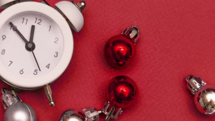 白色小闹钟，红色背景上有圣诞球特写。