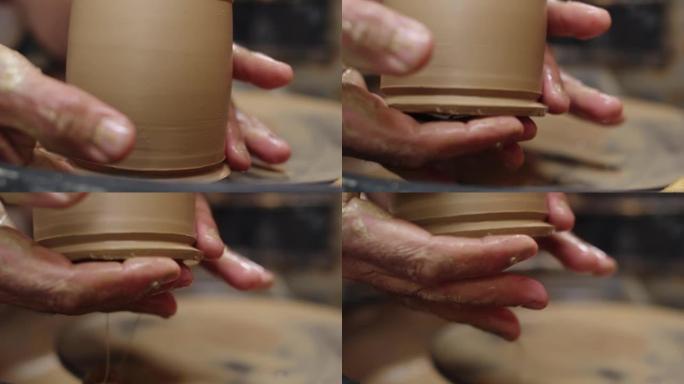 波特的雄性手捡起波特车轮上形成的黏土壶，侧视图。特写。制作陶瓷餐具的概念