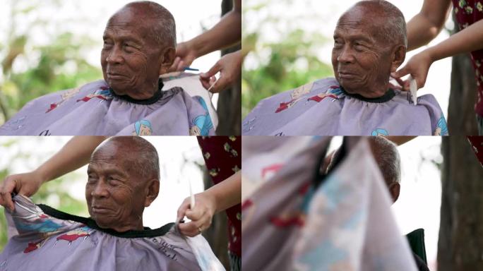 在检疫冠状病毒期间，亚洲妇女正在自家后院剪发和修剪老人的头发