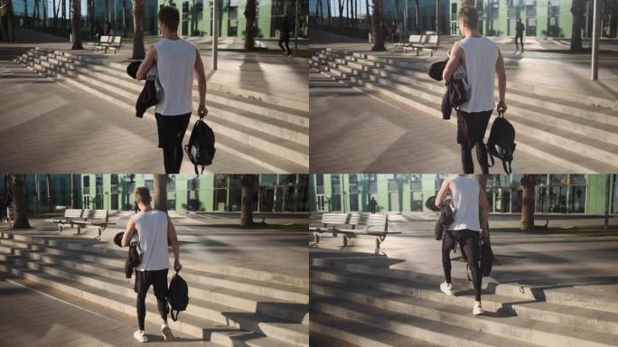 户外训练后，背包健美的家伙在街上行走的后景照片