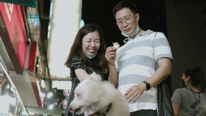 亚洲兄妹游客都觉得在夜街市场和狗一起玩很开心-股票视频