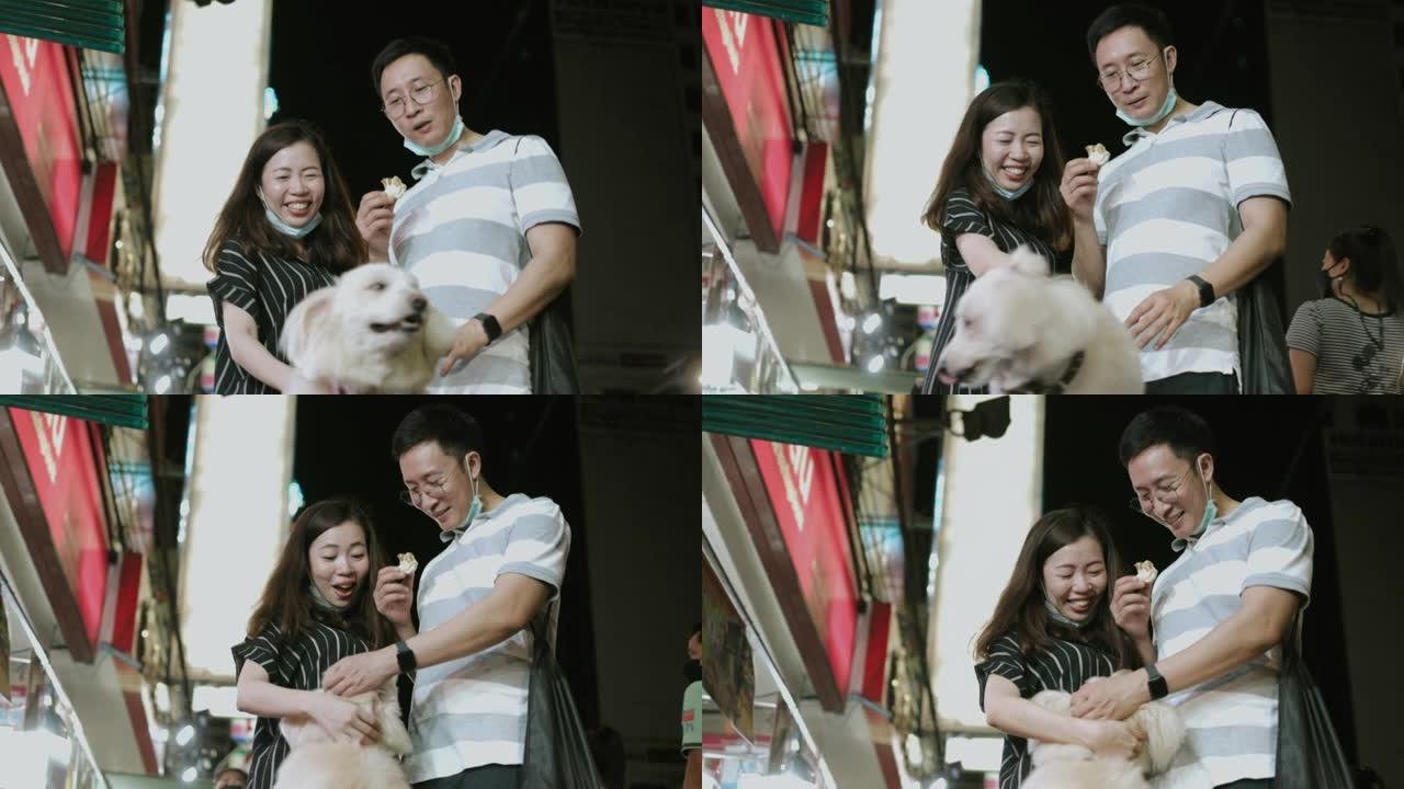 亚洲兄妹游客都觉得在夜街市场和狗一起玩很开心-股票视频