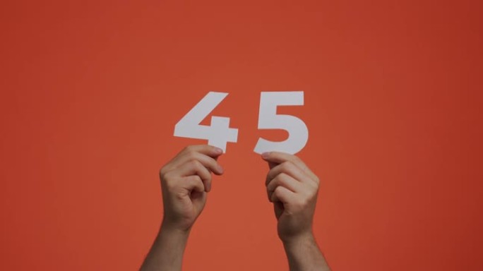 手中有45个数字。显示数字的人，45个由雕刻纸制成的数字，用于投票或数学学习