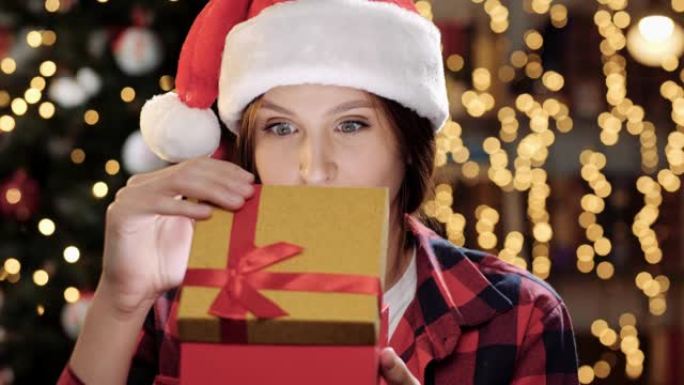 圣诞快乐，新年快乐。女人打开礼物，看着里面的东西，耀眼的明亮光线从盒子里照在她的脸上，女人关闭礼物，