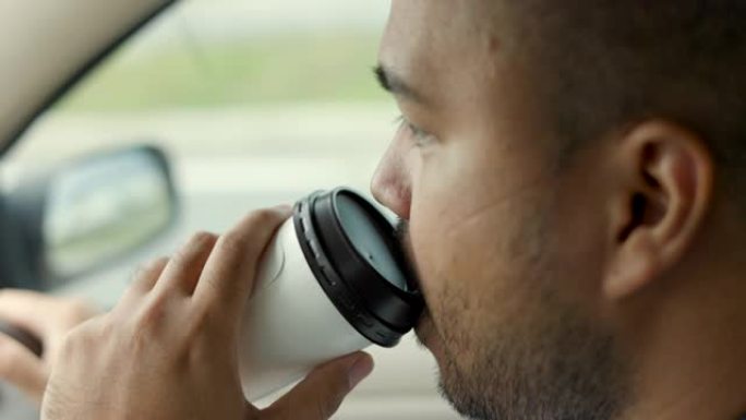 年轻的亚洲男子司机昏昏欲睡。他打了个哈欠，正要睡着。打瞌睡，长时间开车，睡眠不足。他喝热咖啡喝咖啡醒