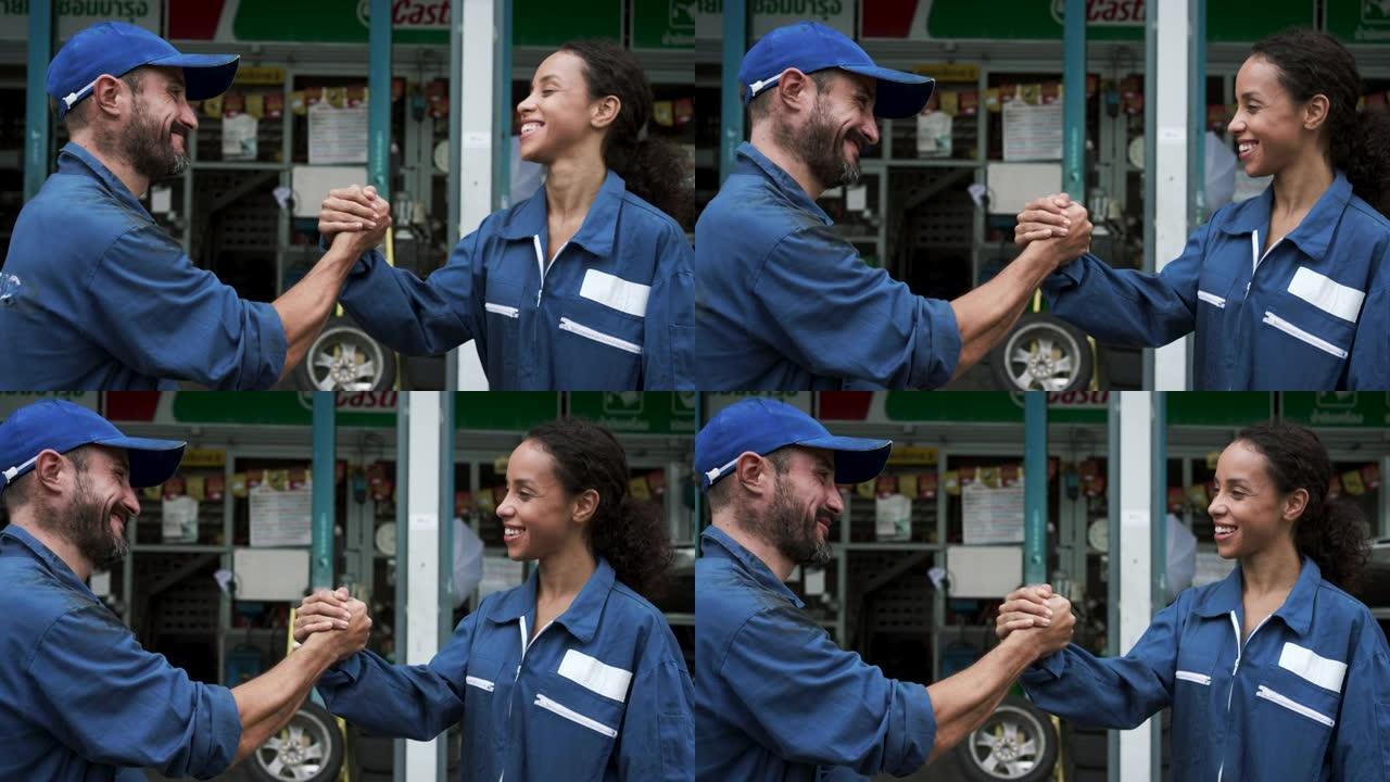 汽车修理工与年轻女性握手，结束了在汽车服务店的合作。握手