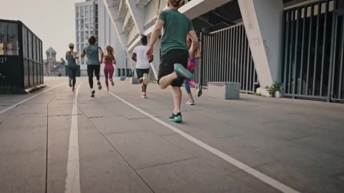 马拉松前训练跑步，积极生活的多种族男女团队的背面视图。跑步俱乐部，一群志同道合的人在清晨沿着城市街道