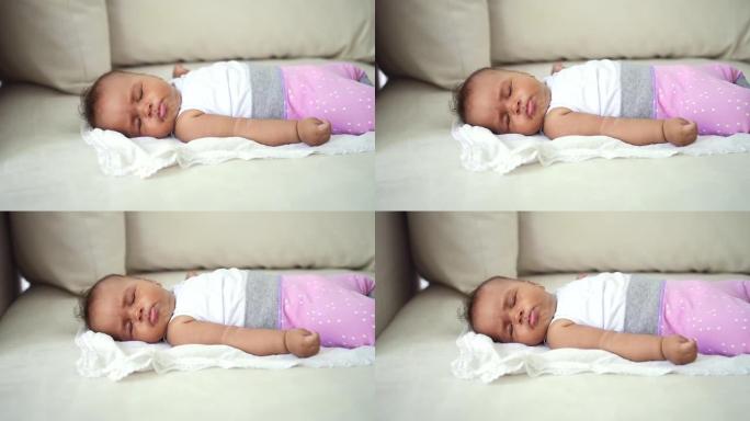 婴儿婴儿独自睡在沙发上。穿着粉色童装的混血幼儿。可爱的无辜孩子