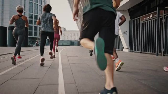 穿着轻便鞋子和衣服的进步耐力运动员穿过城市街道。跑步俱乐部，一群志同道合的人，年轻男女