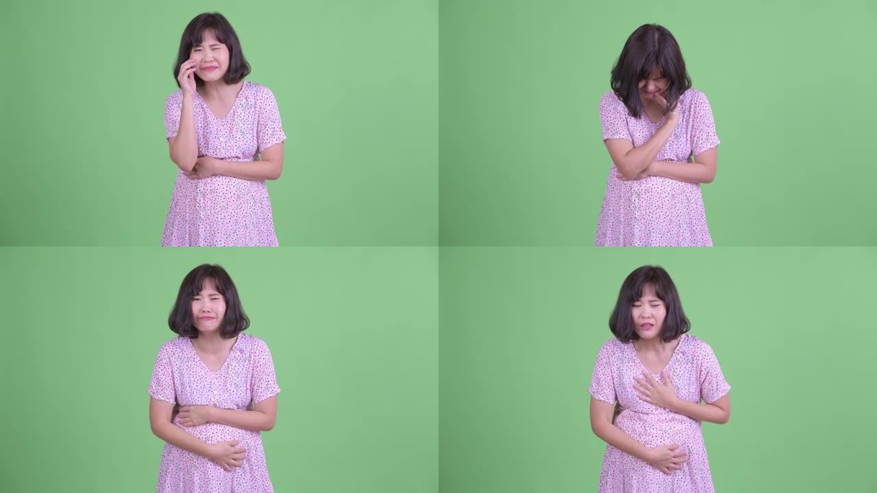 工作室拍摄美丽的亚洲孕妇在绿色工作室背景下感到悲伤