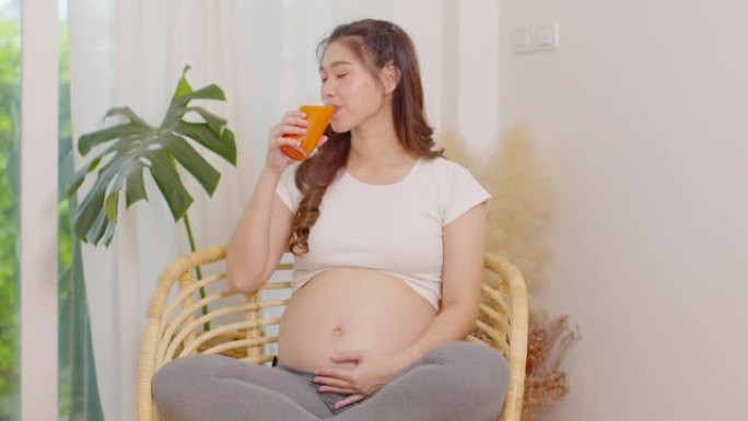 健康孕妇亚洲妇女喝胡萝卜汁维生素a和高维生素c和K，怀孕健康与天然胡萝卜新鲜果汁概念