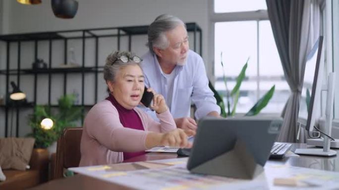 老高级亚洲退休人士企业家在家一起工作，在家隔离远程工作与桌面和智能手机技术设备在家工作