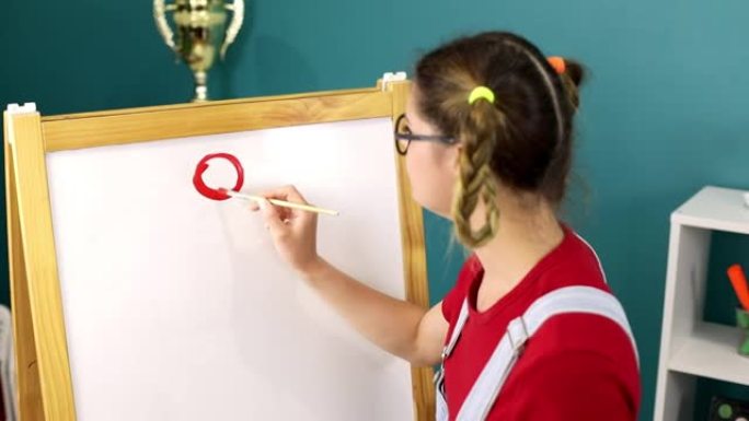 一个可爱的傻女学生在黑板上用颜料画了一个圆圈。