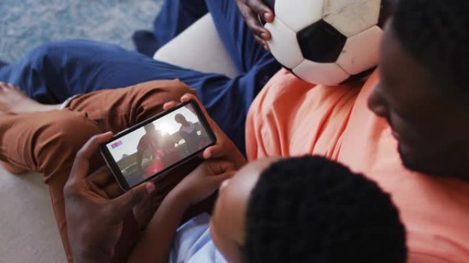 父亲和儿子在家里用智能手机看体育赛事