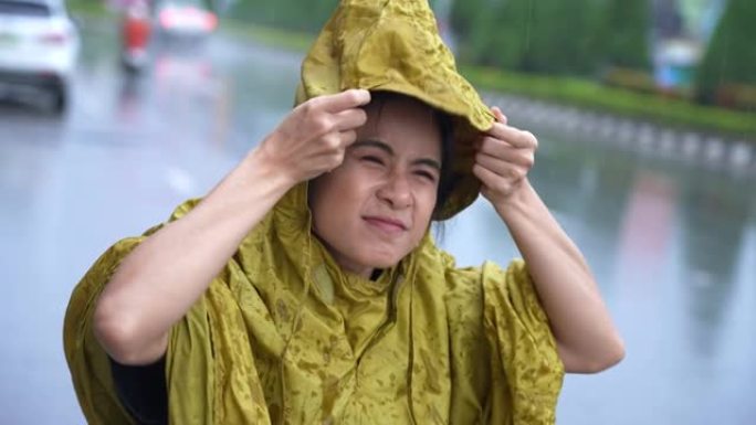 亚洲女孩穿着黄色雨衣匆忙穿上连帽衫，开始下雨，雨季天气气候倾盆大雨，外出工作时运气不好淋湿，高峰时间