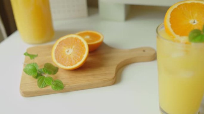 新鲜健康的橘子柑橘汁在玻璃和半个橘子在木板上的白色桌子，准备健康的早餐从天然成分。桌上的自制果汁。有