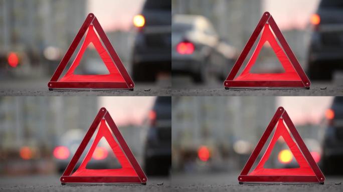 红色紧急停车标志在破碎的模糊汽车后面，夜间城市街道路边闪烁着灯光。