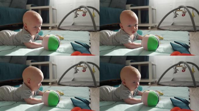 可爱的快乐宝宝玩玩具躺在肚子上的游戏垫上，三个月大男婴的脸特写。
