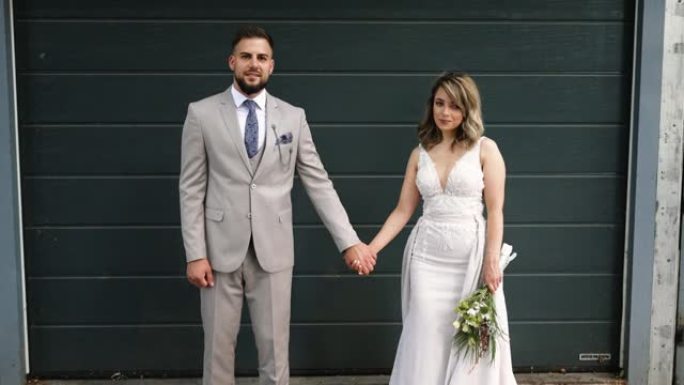 年轻的婚礼夫妇在车库门前摆姿势