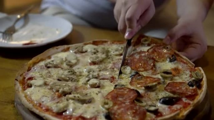 意大利薄薄的意大利辣香肠橄榄披萨一半，蘑菇火腿切成薄片，以供分享