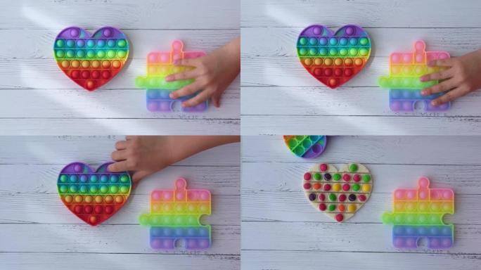 popit形式下的一个孩子发现了一个带有多色糖衣的心形巧克力棒。孩子玩彩虹流行它烦躁玩具。推气泡烦躁