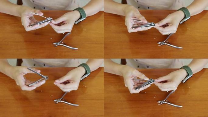 亚洲妇女在家里用指甲剪在木桌上的指甲上手工切割