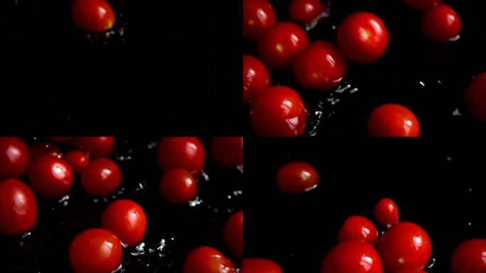 把红色的樱桃西红柿掉进水里。洗西红柿。在黑色背景上。慢动作。