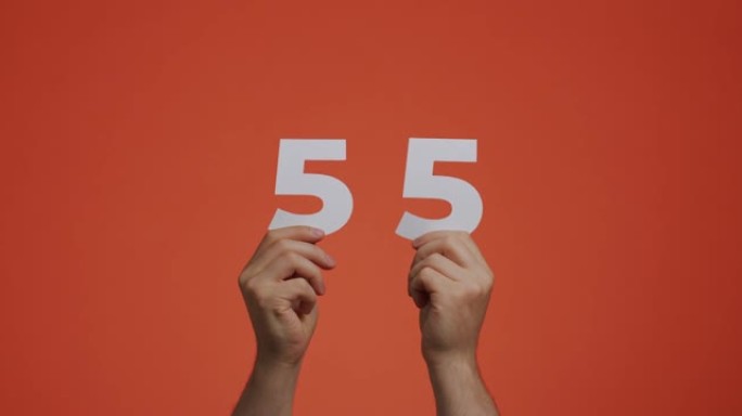 五十五号在手。显示数字的人，55个由雕刻纸制成的数字，用于投票或数学学习