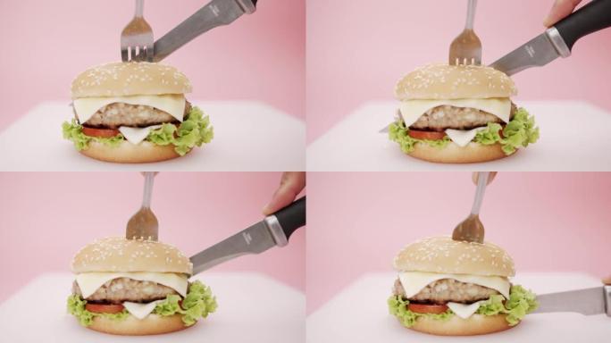 刀叉切割切割汉堡孤立在粉红色背景，快餐概念。