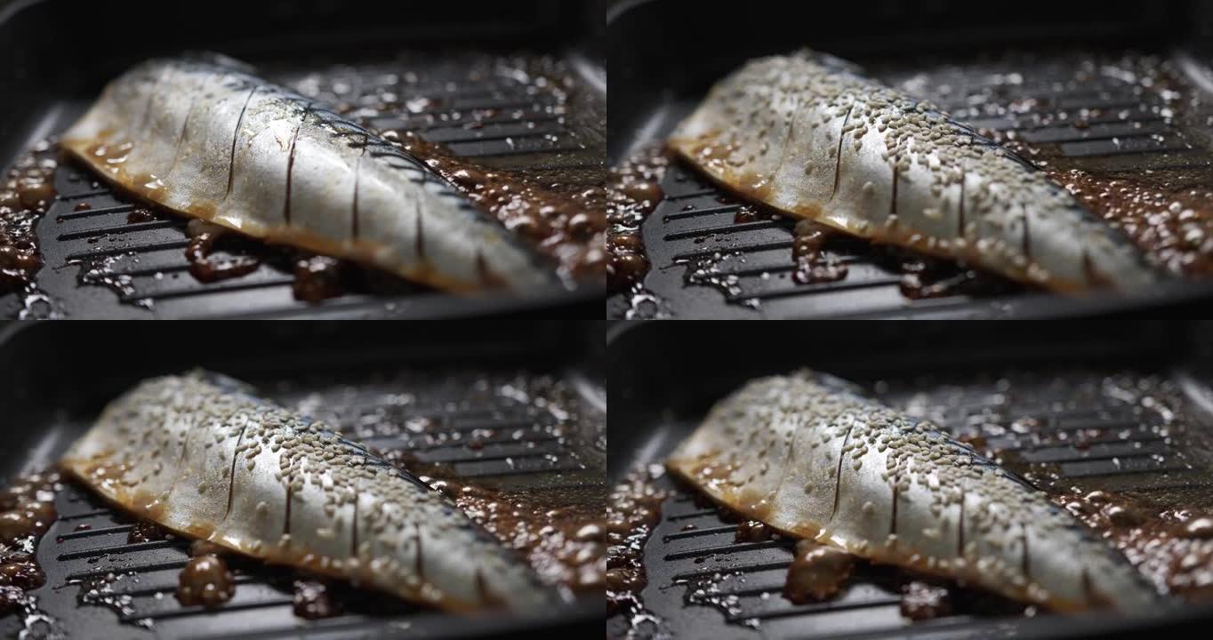 烹饪倒入白芝麻放在黑色热锅上烤的Saba鱼。