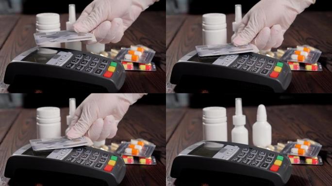 一个戴着手套的女人用卡在药房支付药品的特写镜头。