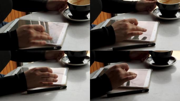 一个女人坐在咖啡馆里，在平板电脑上工作