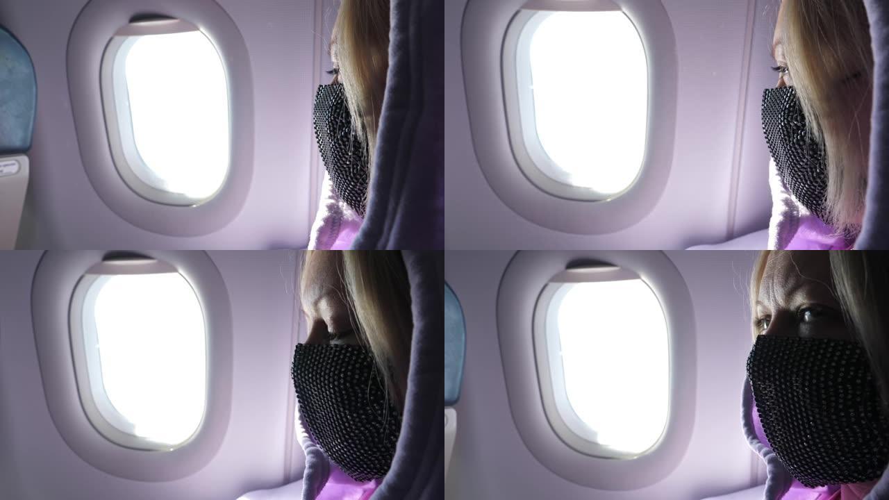 飞行时，在靠近窗户的飞机上戴着防护面罩的女人。世界新型冠状病毒肺炎情况下的新正常旅行