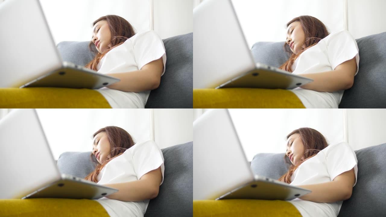 疲倦的女人睡在沙发的笔记本电脑前，在家工作过度