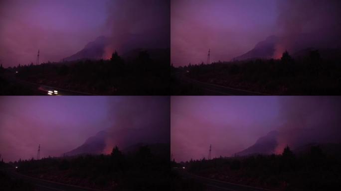 汽车在黄昏时分因大火而在烟雾中沿着山路行驶