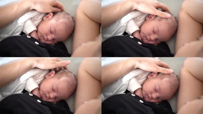 妈妈抚摸一个熟睡的新生儿的头