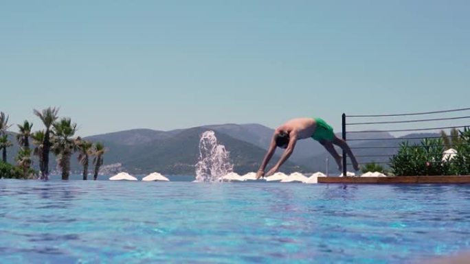 男子跳到豪华度假村的游泳池。慢动作