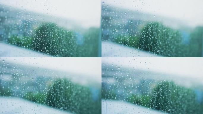 慢动作场景窗玻璃上的水滴，以模糊绿色公园背景为雨季设计理念