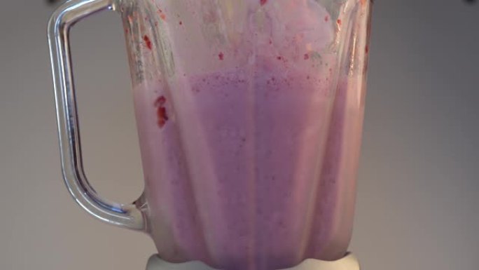 搅拌器的玻璃容器，其中冰淇淋加入红色，成熟的草莓捣碎。制备健康的有机奶昔，草莓冰沙，奶油。