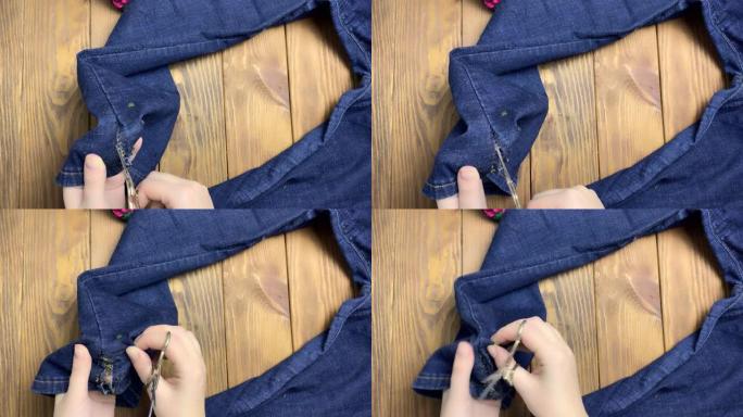 女人的手在牛仔裤上用剪刀解开接缝。