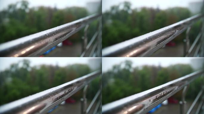 下雨了。下雨。特写。雨滴滴在阳台金属栏杆的光滑表面上，并在雨中向下流动。夏季雨天