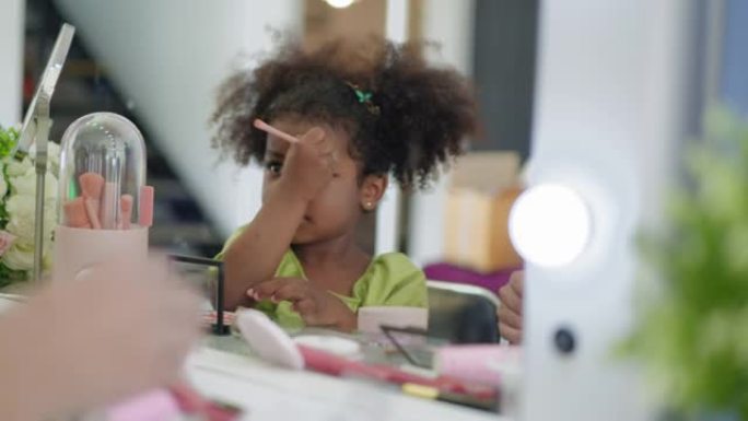 非洲十几岁的女儿试图在家里的卧室里，在母亲的化妆品柜台上使用睫毛夹在眉毛上，充满乐趣，快乐和爱心，积