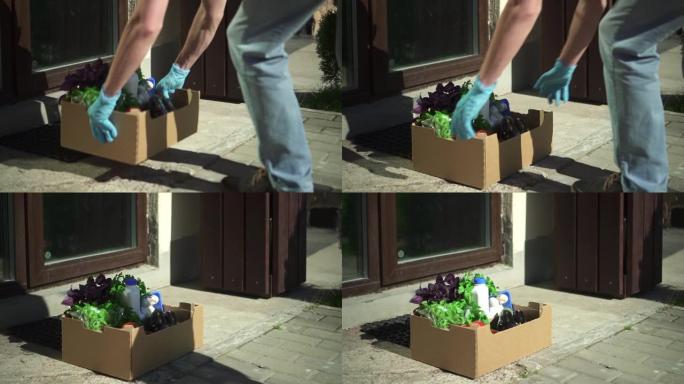 男性快递员将一盒杂货放在室外spbd房屋门口的地板上