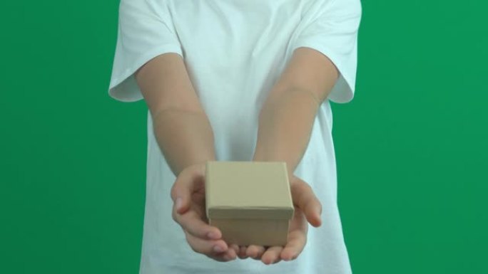 十几岁的男孩伸出手，在绿屏色度关键背景上给小礼品盒