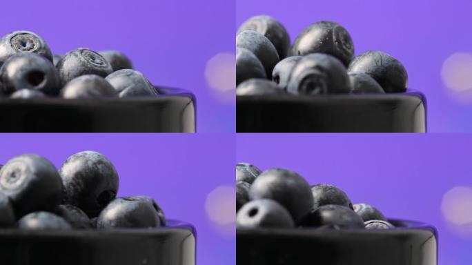成熟的甜蓝莓浆果在黑色陶瓷杯中的深蓝色背景特写。